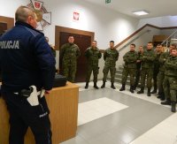 Policjant Wydziału Ruchu Drogowego udziela odpowiedzi na zadawane pytania, wokół niego stoją żołnierze Terytorialnej Służby Wojskowej