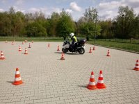 Policjant Ruchu Drogowego jeżdżąc na motocyklu doskonali umiejętności omijania przeszkód, w tym przypadku pachołków