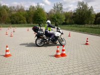 Policjant Ruchu Drogowego jeżdżąc na motocyklu doskonali umiejętności omijania przeszkód, w tym przypadku pachołków