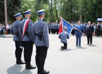 Komendant Powiatowy Policji w Hajnówce klęcząc całuje sztandar komendy.