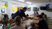 Dzielnicowy z  Komendy Powiatowej Policji w Hajnówce rozdaje uczestnikom spotkania elementy odblaskowe