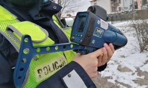 Zdjęcie przedstawia ręce policjanta ruchu drogowego, który trzyma urządzenie do pomiarów prędkości.