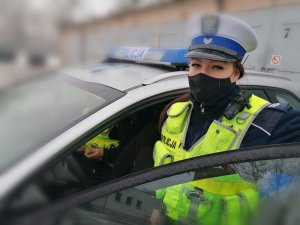 Zdjęcie przedstawia policjantkę ruchu drogowego stojącą przy radiowozie.