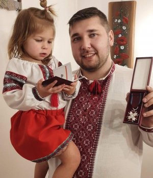 Zdjęcie przedstawia Piotra Ostaszewskiego z córeczką, trzymających odznaczenia.