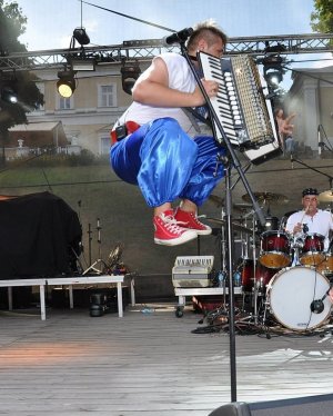 Zdjęcie przedstawia Piotrka Ostaszewskiego z akordeonem na scenie.