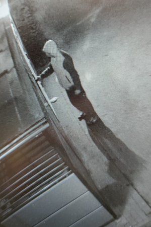Zdjęcie z kamery monitoringu przedstawia podejrzanego w trakcie otwierania wiaty śmietnikowej.