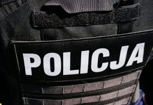 Zdjęcie przedstawia taktyczna kamizelkę policyjną, w kolorze czarnym z białym napisem &quot;Policja&quot;.
