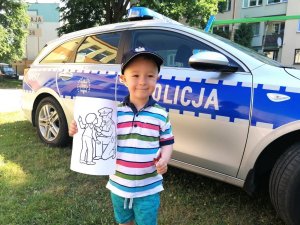 Zdjęcie przedstawia chłopca trzymającego kolorowankę z policjantem.