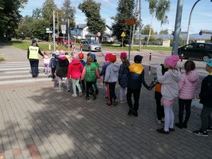 Dzieci na spacerze edukacyjnym z policjantką.