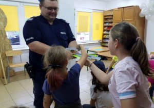 Dzielnicowy rozdaje opaski odblaskowe dzieciom