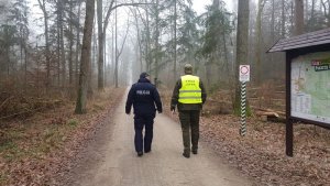 Dzielnicowy ze Strażnikiem Leśnym idą droga lesną