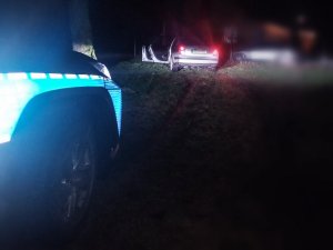Zdjęcie przedstawia tył samochodu, który uderzył w drzewo. Na zdjęciu widać też część policyjnego radiowozu.