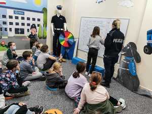 Policjanci i dzieci w trakcie spotkania profilaktycznego w sali.
