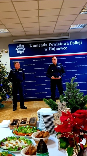 Zdjęcie przedstawia policjantów w umundurowaniu służbowym kolory granatowego, zgromadzonych w świetlicy przy wigiljnym stole.