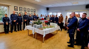 Zdjęcie przedstawia policjantów w umundurowaniu służbowym kolory granatowego, zgromadzonych w świetlicy przy wigiljnym stole.