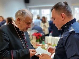 Zdjęcie przedstawia policjantów w umundurowaniu służbowym kolory granatowego, zgromadzonych w świetlicy przy wigiljnym stole.