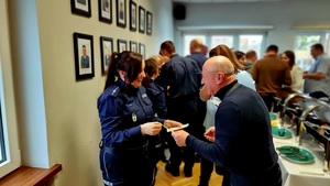 Zdjęcie przedstawia policjantów w umundurowaniu służbowym kolory granatowego, zgromadzonych w świetlicy przy wigiljnym stole.