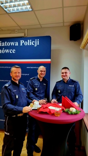 Zdjęcie przedstawia policjantów w umundurowaniu służbowym kolory granatowego, zgromadzonych w świetlicy przy wigiljnym stole.