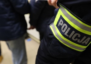 Zdjęcie przedstawia rękaw kurtki koloru czarnego z opaską odblaskową z napisem &quot;Policja&quot;