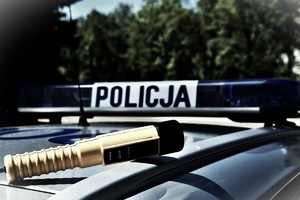Alkomat koloru żółtego leżący na dachu radiowozu.