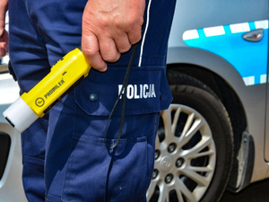 Reka policjanta  w mundurze, trzymającego alkomat.