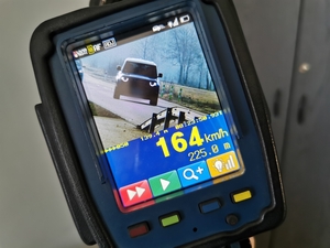 Zdjęcie przedstawia ręczny miernik prędkości z wykonanym pomiarem 164 kilometrów na godzinę.